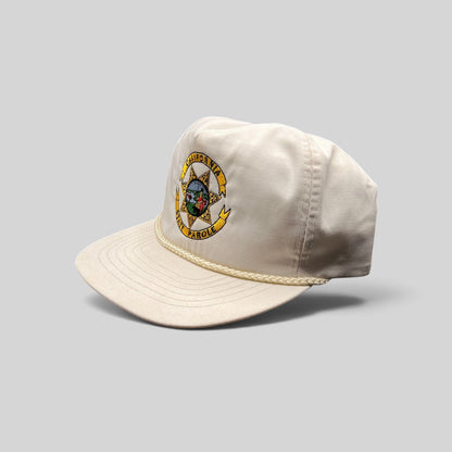 Raree Finds vintage 90s white Otto snapback hat with embroidered California State Parole emblem and braided rope brim.