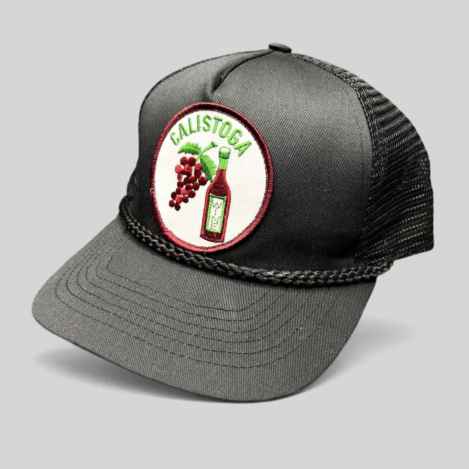 Raree Finds vintage black trucker hat with Calistoga wine bottle and grape patch, braided rope, and mesh back.