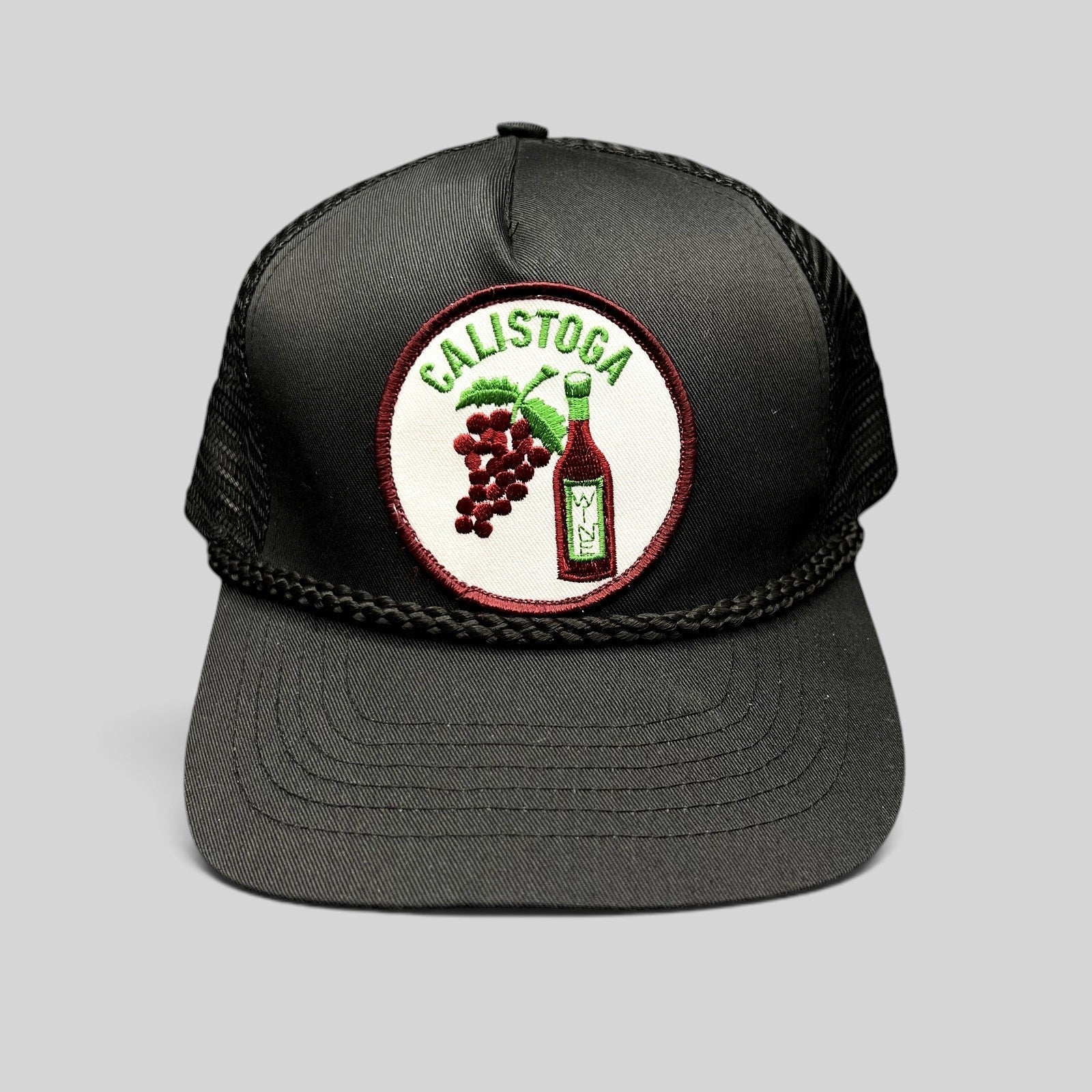 Raree Finds vintage black Calistoga Wine trucker hat with embroidered grape and bottle patch and braided rope brim