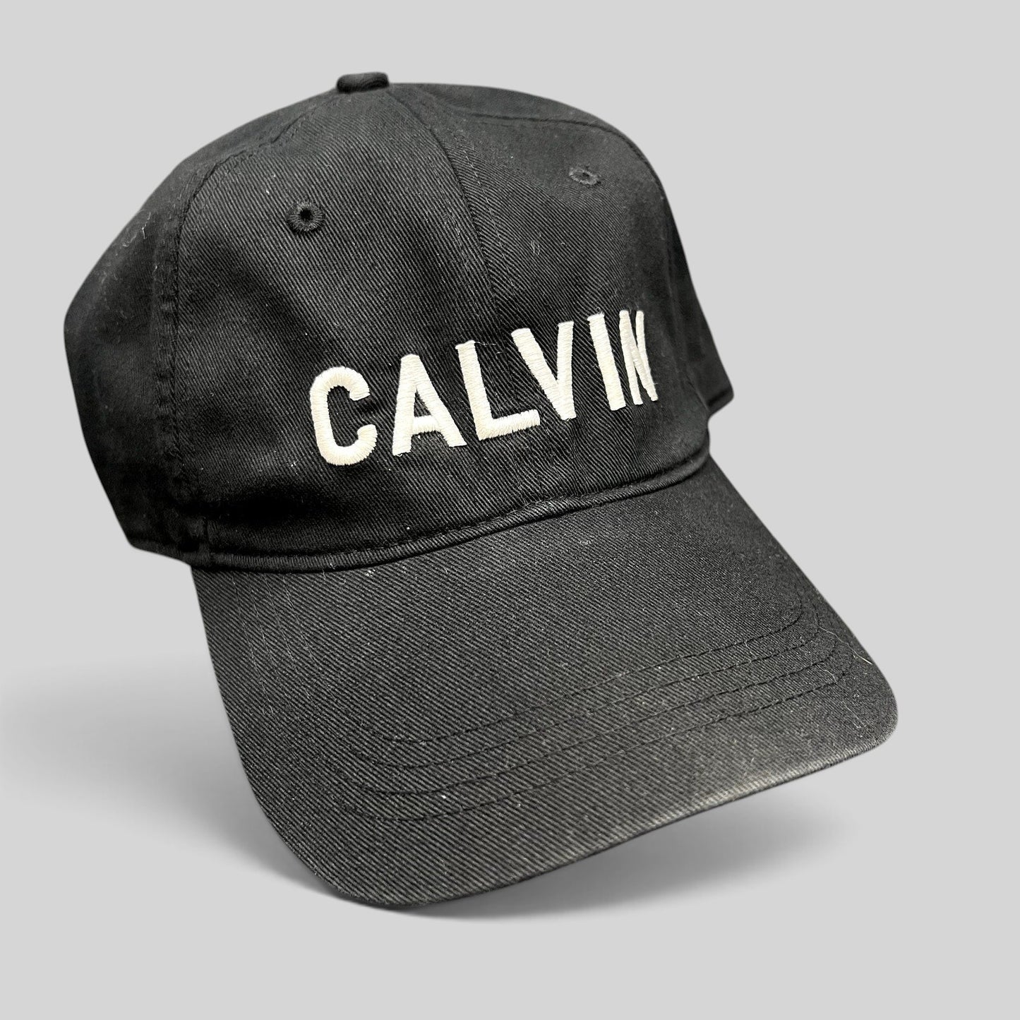Raree Finds vintage black Calvin Klein cotton strapback hat with white CALVIN embroidery and a curved brim.