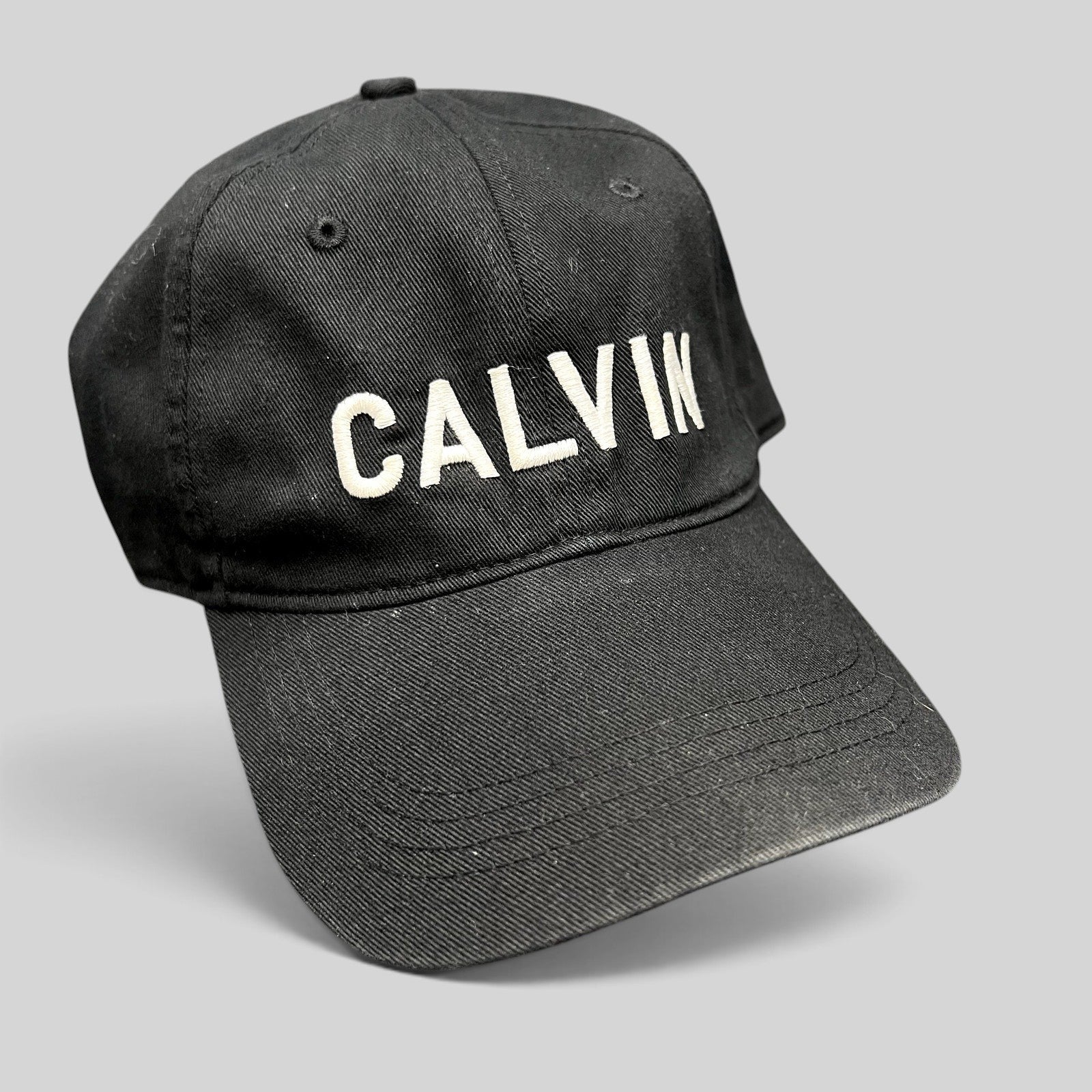Raree Finds vintage black Calvin Klein cotton strapback hat with white CALVIN embroidery and a curved brim.
