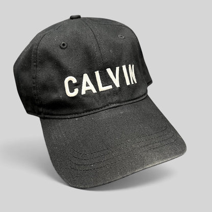 Raree Finds vintage black Calvin Klein cotton strapback hat with white CALVIN embroidery and a curved brim.