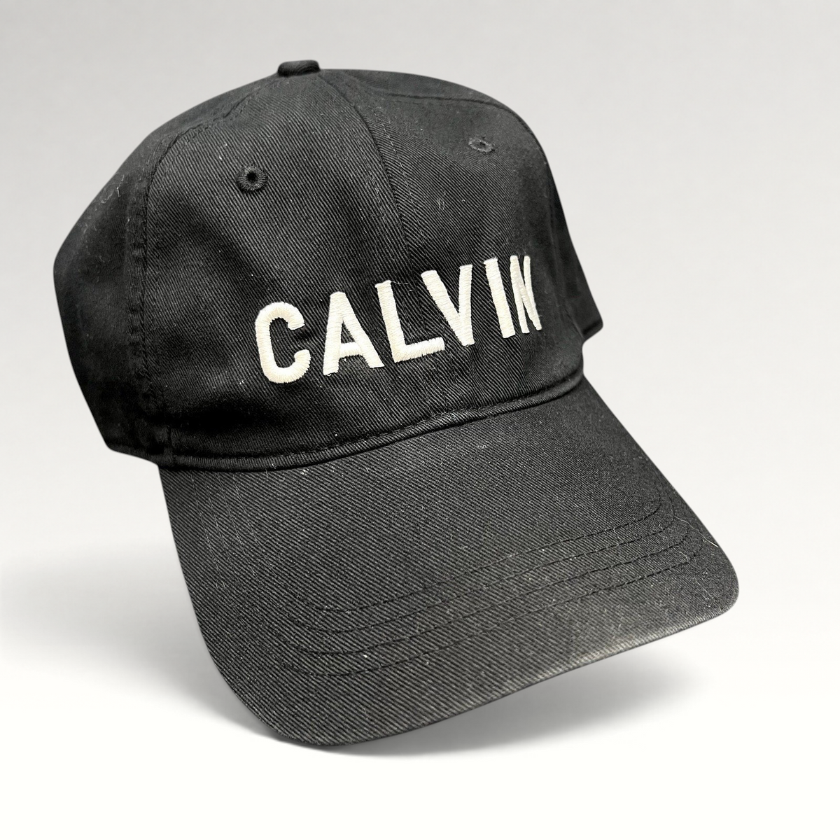 Raree Finds vintage black Calvin Klein cotton strapback hat with white CALVIN embroidery and a curved brim.