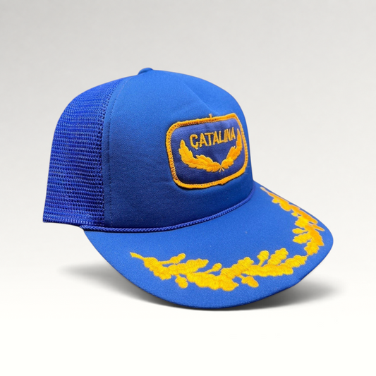 Raree Finds vintage 1980s royal blue foam trucker hat with gold Catalina patch and laurel leaf embroidery on the brim.