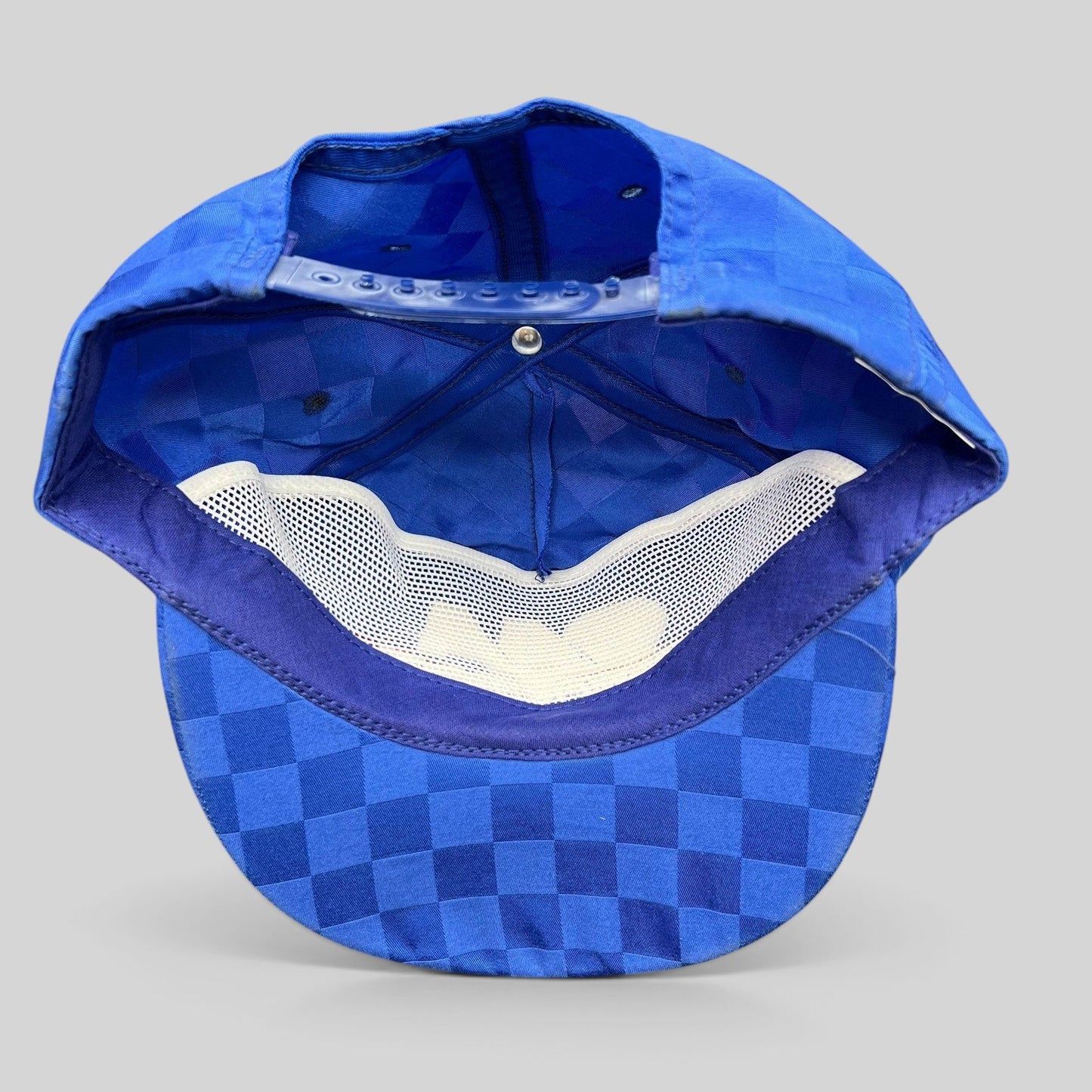 Raree Finds vintage royal blue checkered snapback hat showing the interior mesh lining and adjustable plastic strap.