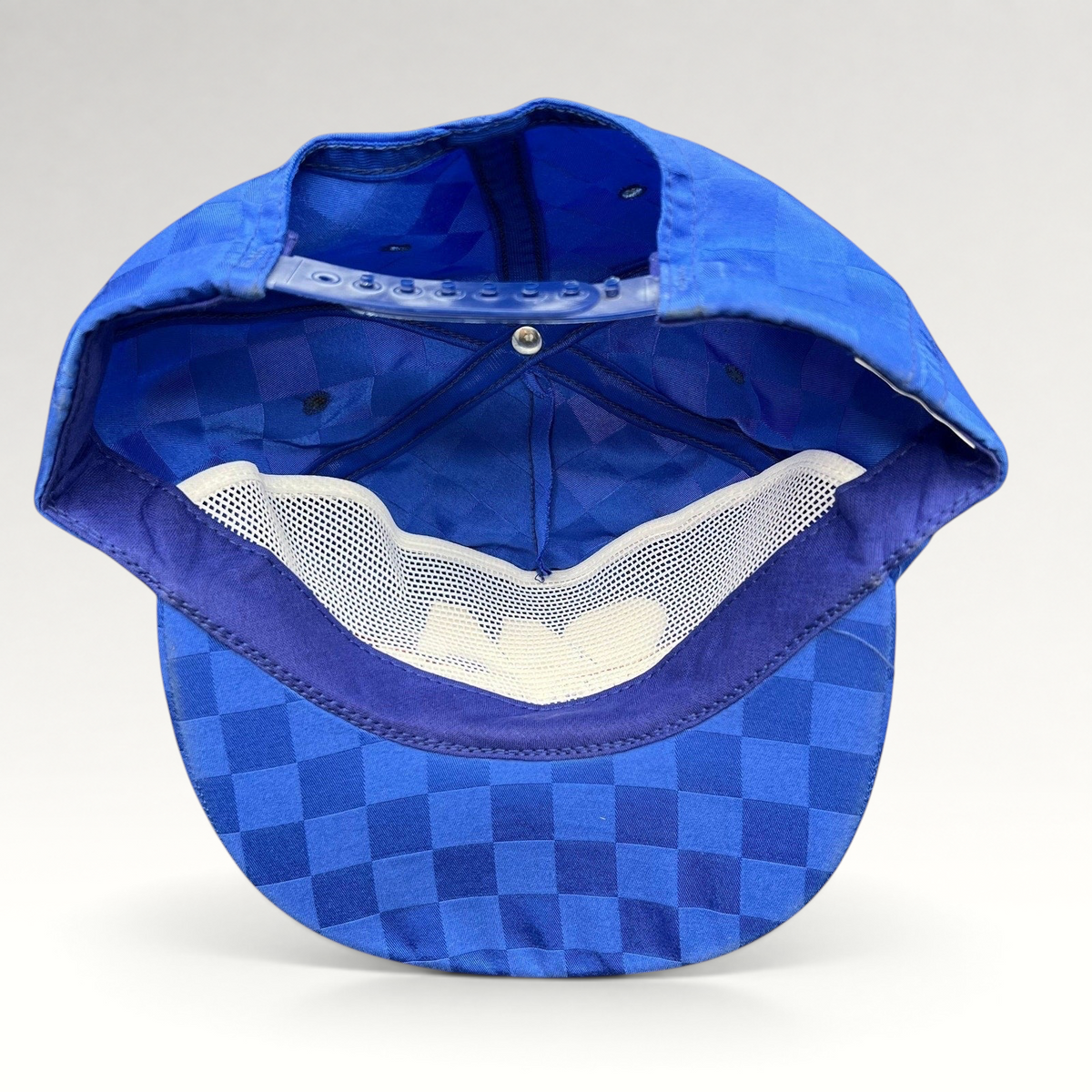 Raree Finds vintage royal blue checkered snapback hat showing the interior mesh lining and adjustable plastic strap.