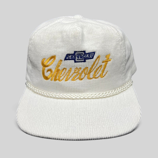 Raree Finds vintage 1980s white corduroy Chevrolet strapback hat with gold script logo and braided rope brim detail.