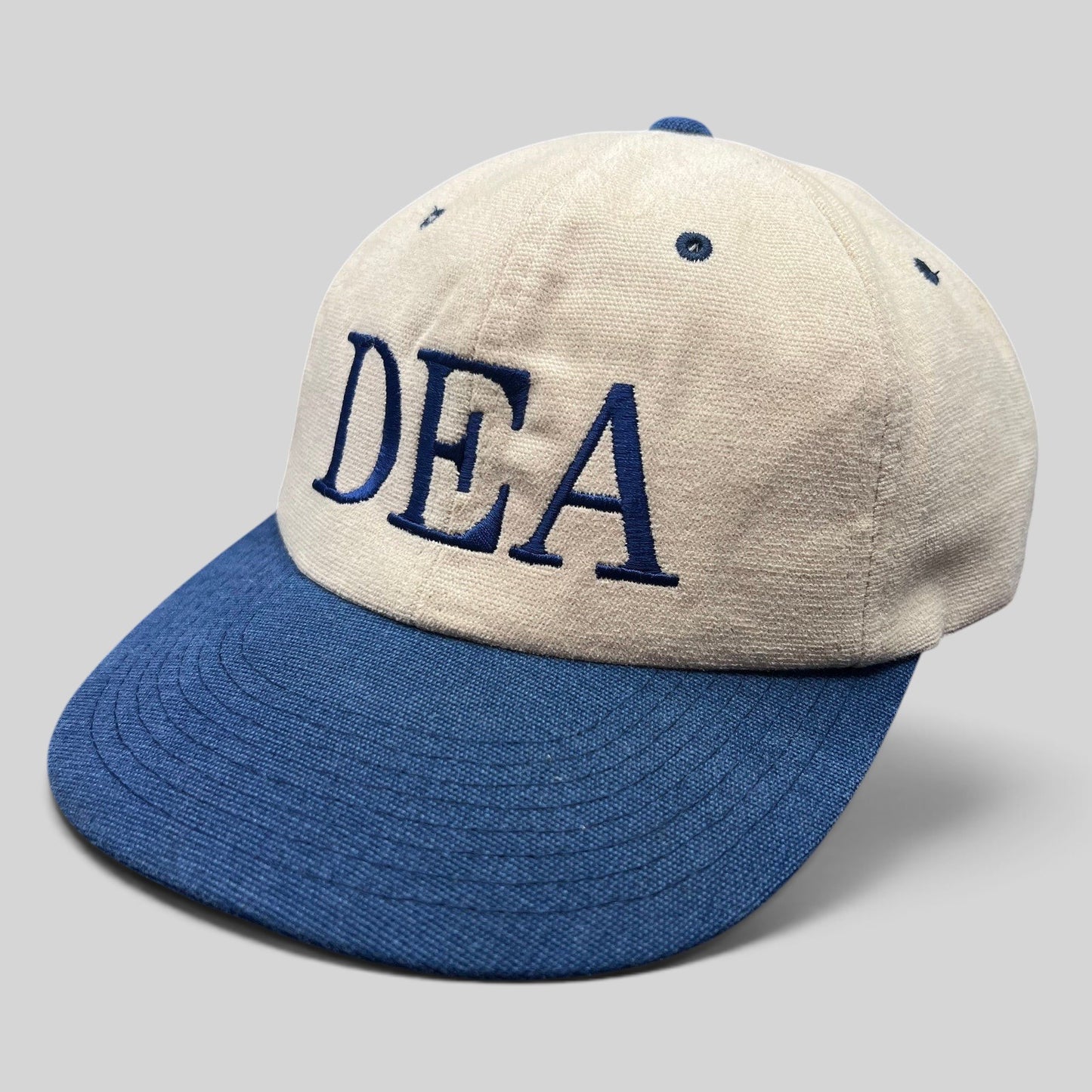 Raree Finds vintage Yupoong DEA strapback hat with a tan cotton crown, navy blue brim, and embroidered lettering.