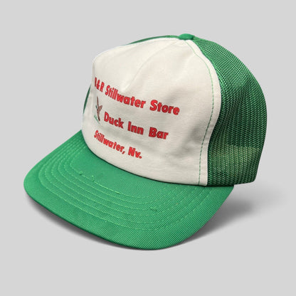 Raree Finds vintage trucker hat with white foam front, green mesh back, and red Duck Inn Bar embroidery on a green brim.