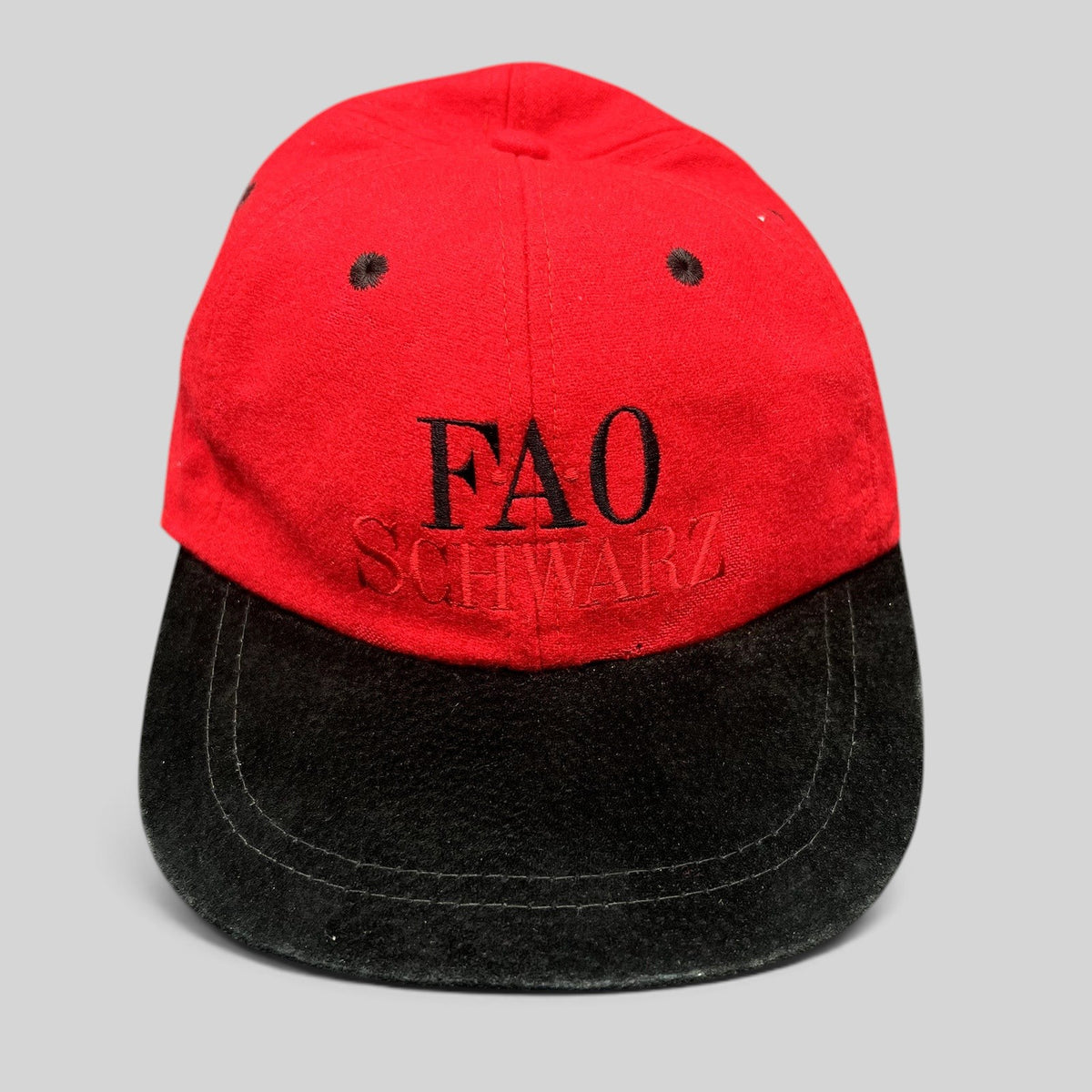 Raree Finds vintage FAO Schwarz youth strapback hat in red wool with a black brim and embroidered logo.