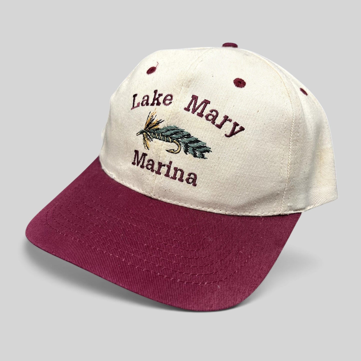 Raree Finds vintage Lake Mary Marina snapback hat with cream crown, burgundy bill, and fishing fly lure embroidery.