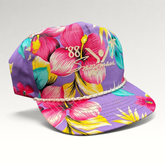 Raree Finds vintage 1988 Snowmass snapback hat in purple with a tropical floral print, rope brim, and skier graphic.