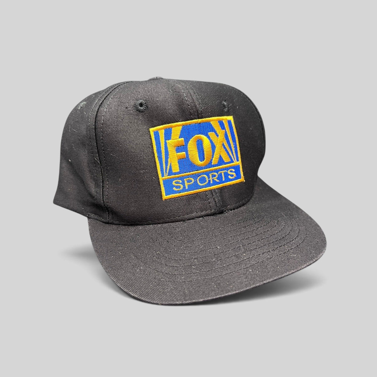 Raree Finds vintage 90s black cotton snapback hat featuring an embroidered gold and royal blue FOX Sports logo