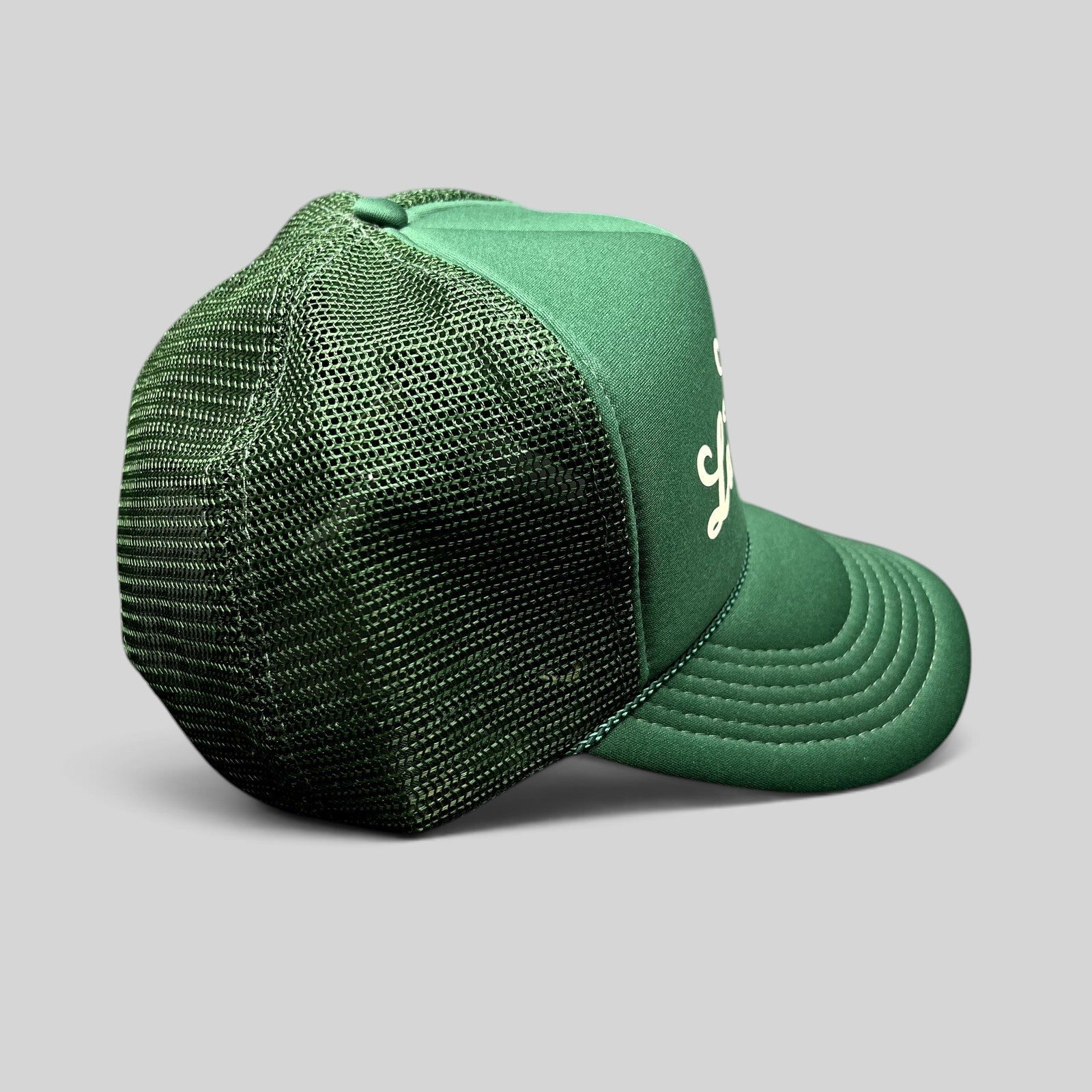 Raree Finds vintage green lemonade mesh trucker hat with white script logo, foam front, and braided rope detail.