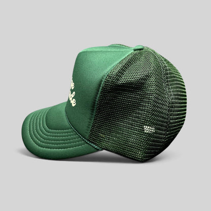 Raree Finds vintage green foam trucker hat with mesh back, white script logo, and braided rope detail on the brim.