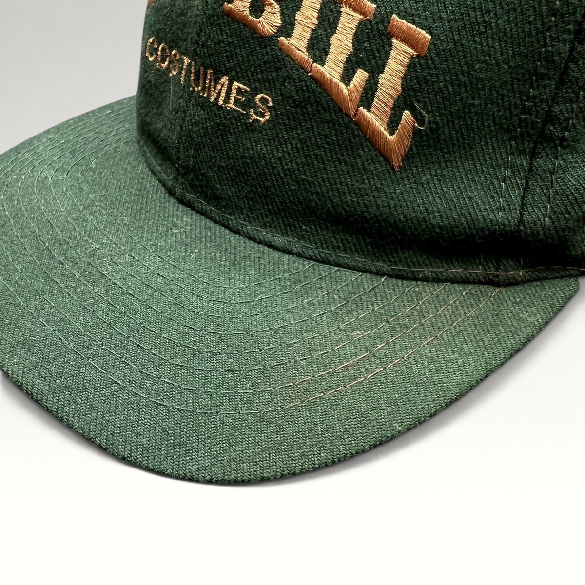 Raree Finds vintage dark green Otto Cap snapback hat with brown Wild Bill Costumes embroidery on the structured crown.