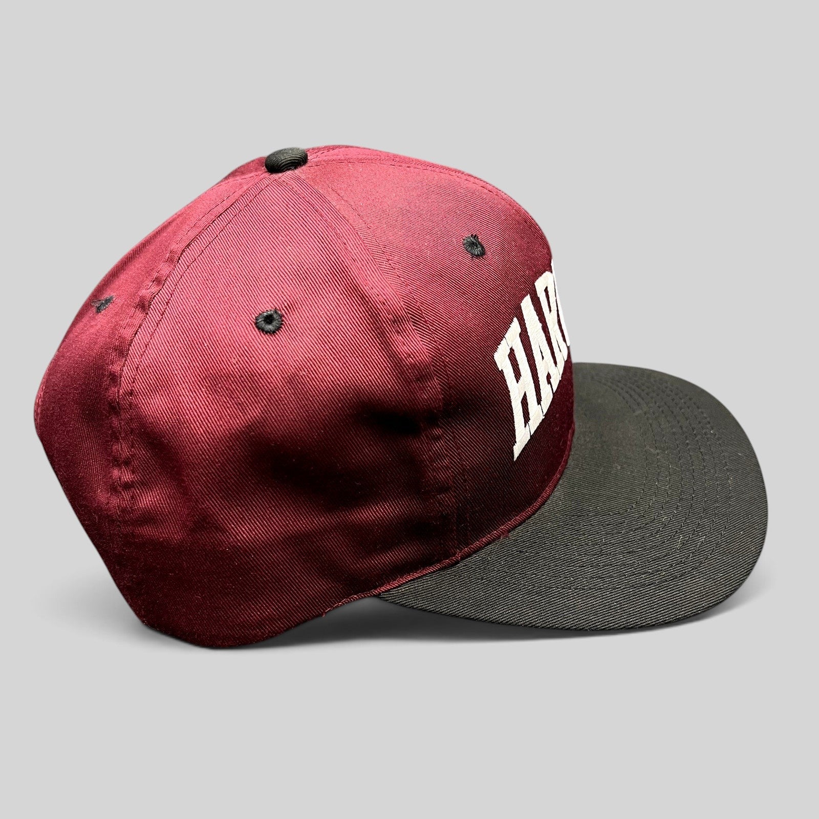 Raree Finds vintage Harvard University snapback hat with crimson crown, black brim, and white embroidered lettering.