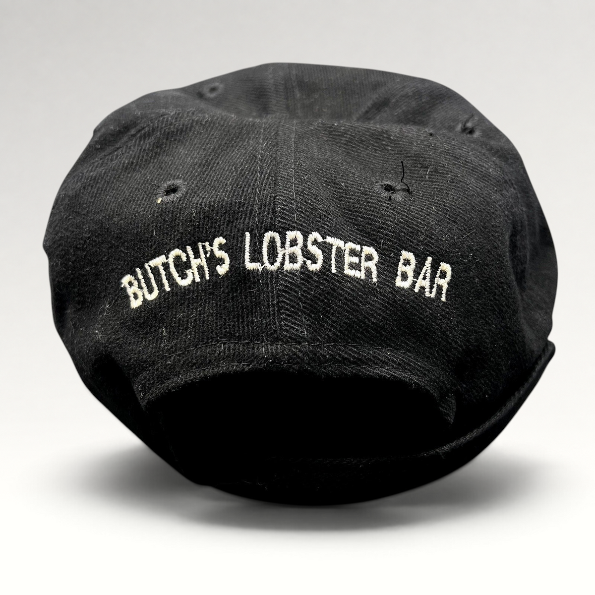 Raree Finds vintage 1990s black strapback hat featuring white embroidered Butch’s Lobster Bar text on the back