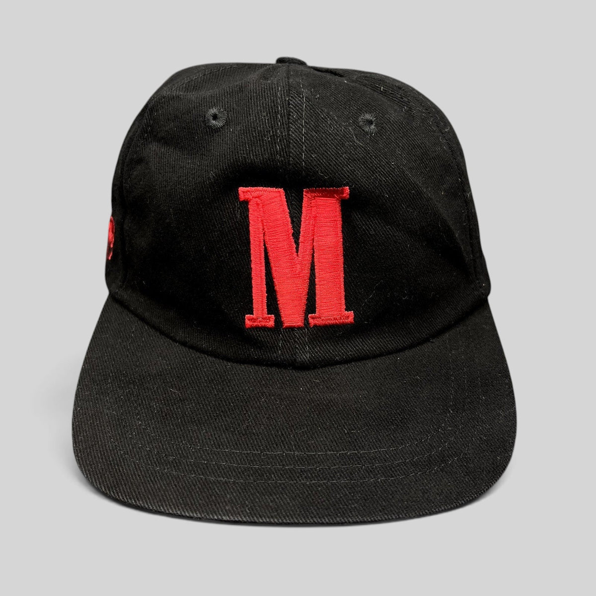 Raree Finds vintage black strapback hat with a large red embroidered M logo on the front and a curved brim.
