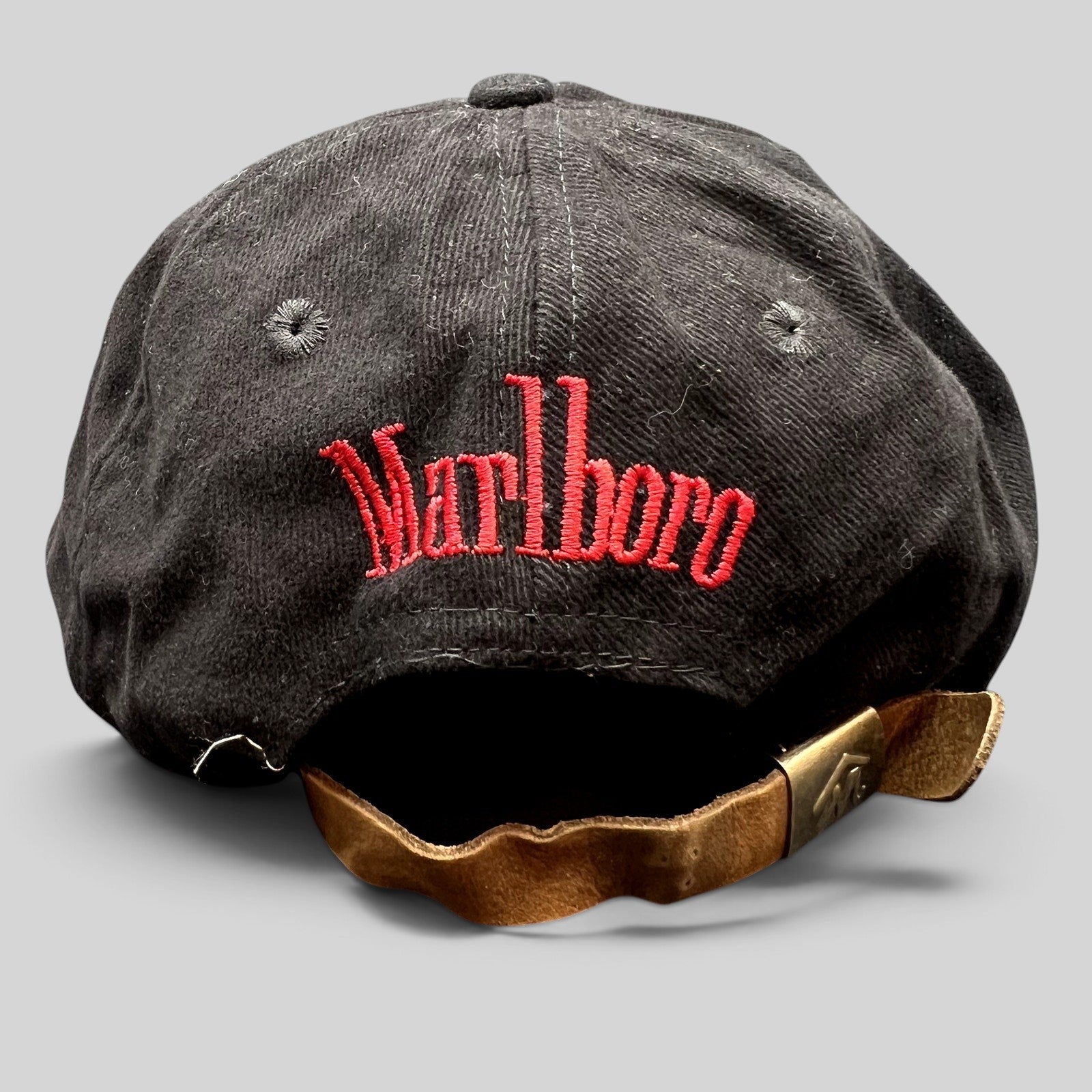 Raree Finds vintage black Marlboro strapback hat with red script embroidery and brown leather strap with brass clasp