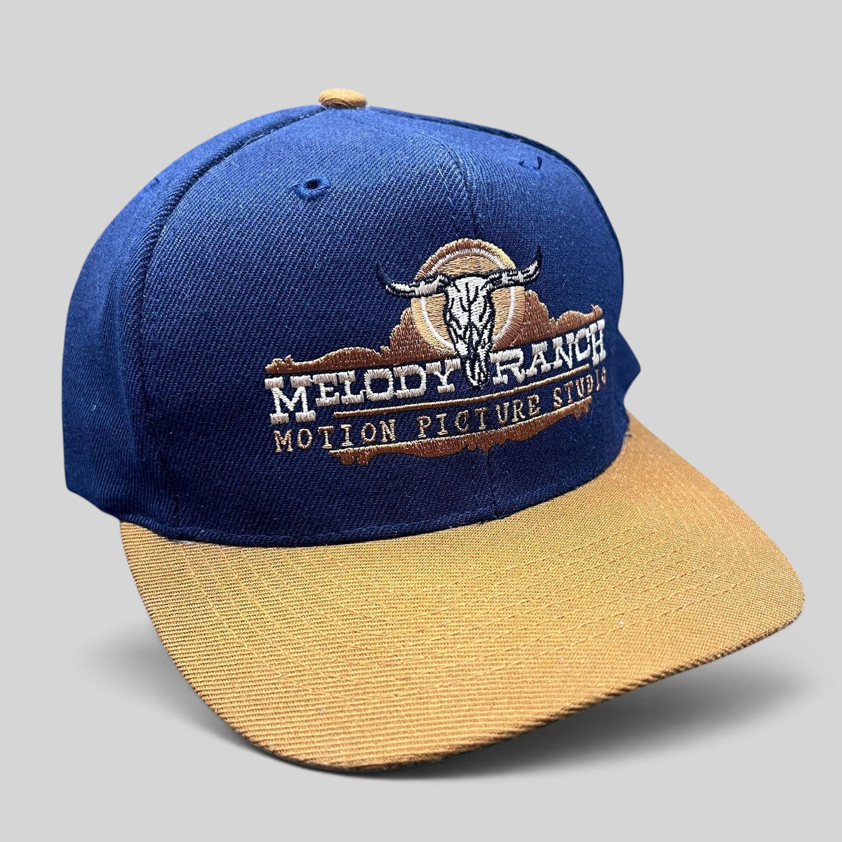 Raree Finds vintage navy and tan snapback hat featuring an embroidered Melody Ranch Motion Picture Studio longhorn logo