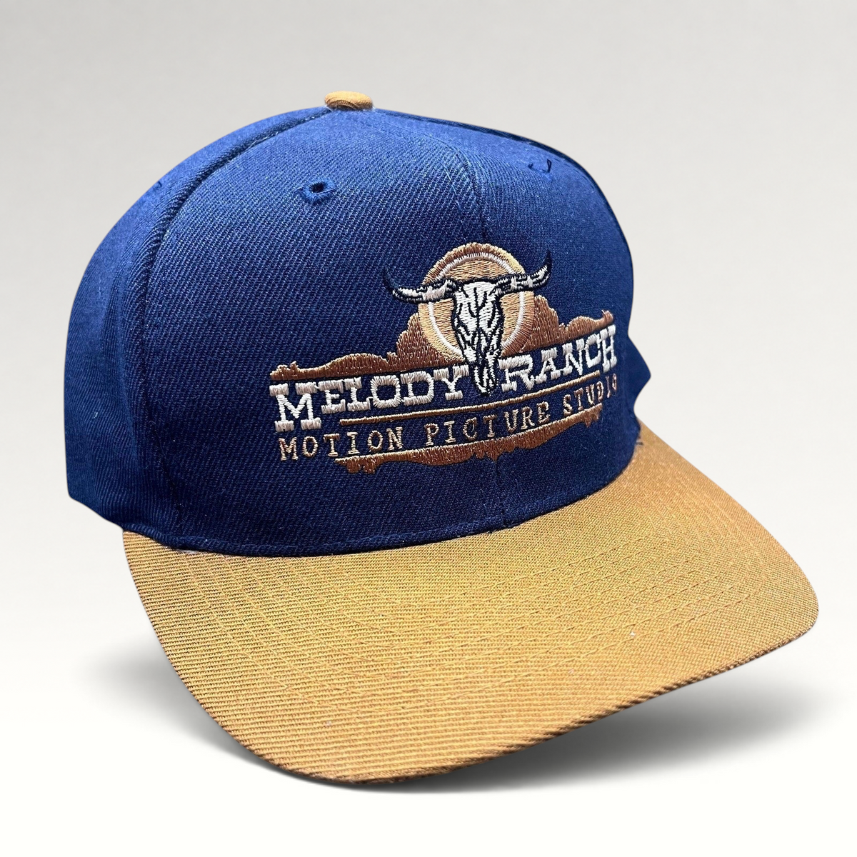 Raree Finds vintage navy and tan snapback hat featuring an embroidered Melody Ranch Motion Picture Studio longhorn logo