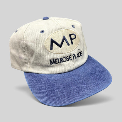 Raree Finds vintage 90s Melrose Place FOX TV show strapback hat with cream crown, blue brim, and embroidered MP logo.