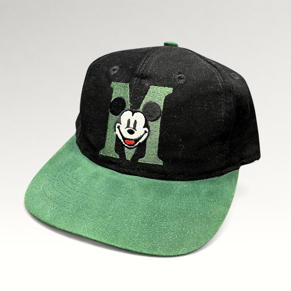 Raree Finds vintage 90s Disney Store black and green snapback hat with embroidered Mickey Mouse M logo on flat brim