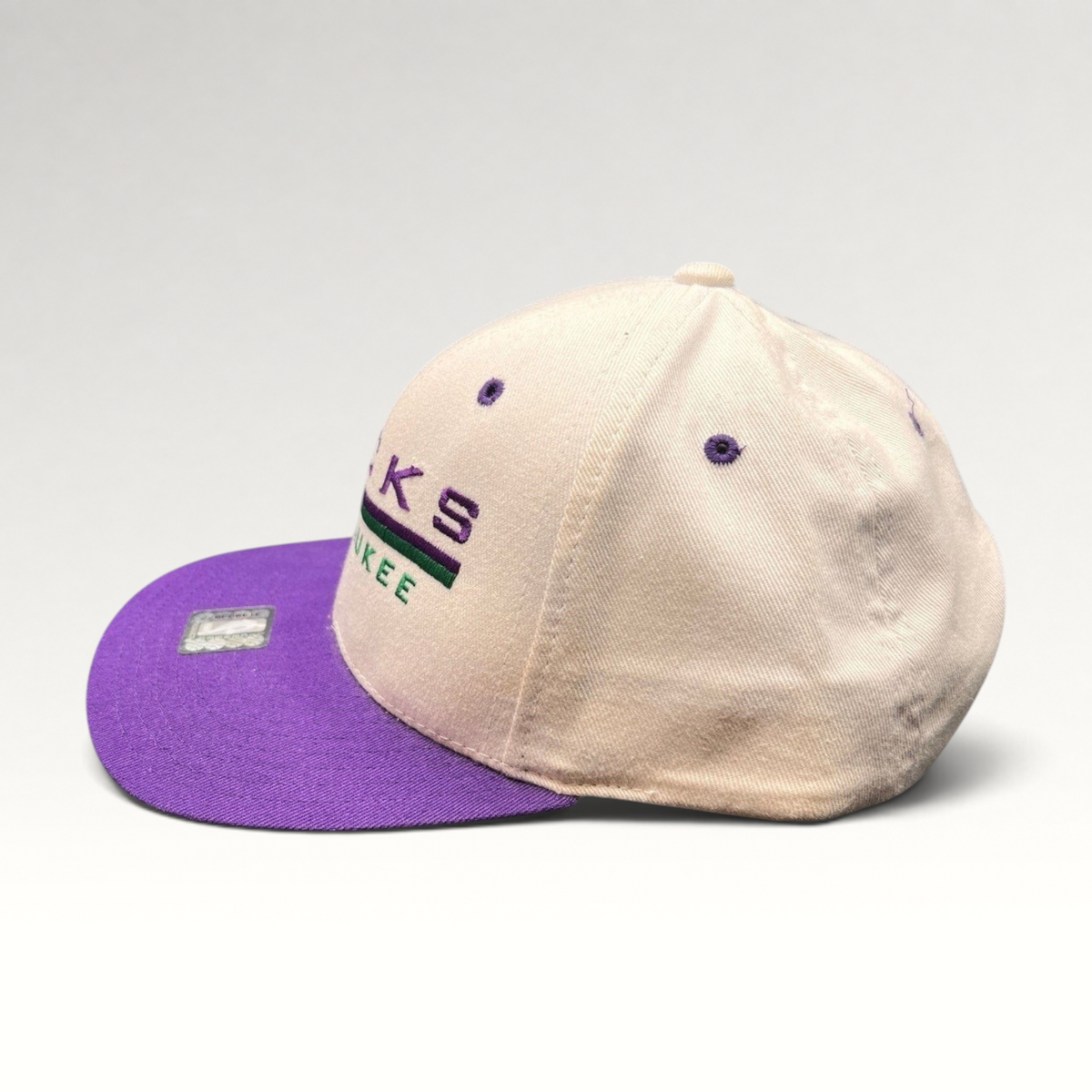 Raree Finds vintage 1990s Milwaukee Bucks snapback hat with a white crown, purple brim, and embroidered team logo.