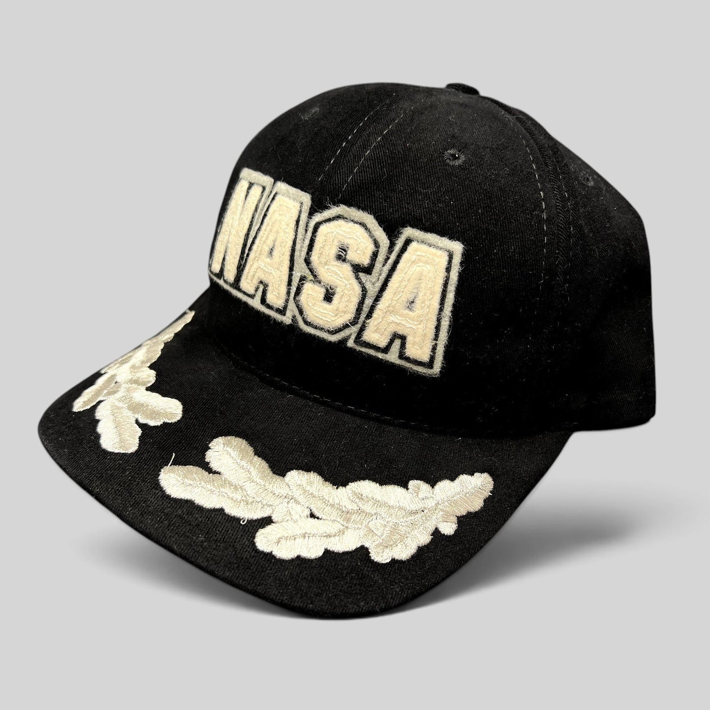 Raree Finds vintage black American Needle NASA strapback hat with cream embroidered logo and leaf brim detailing.