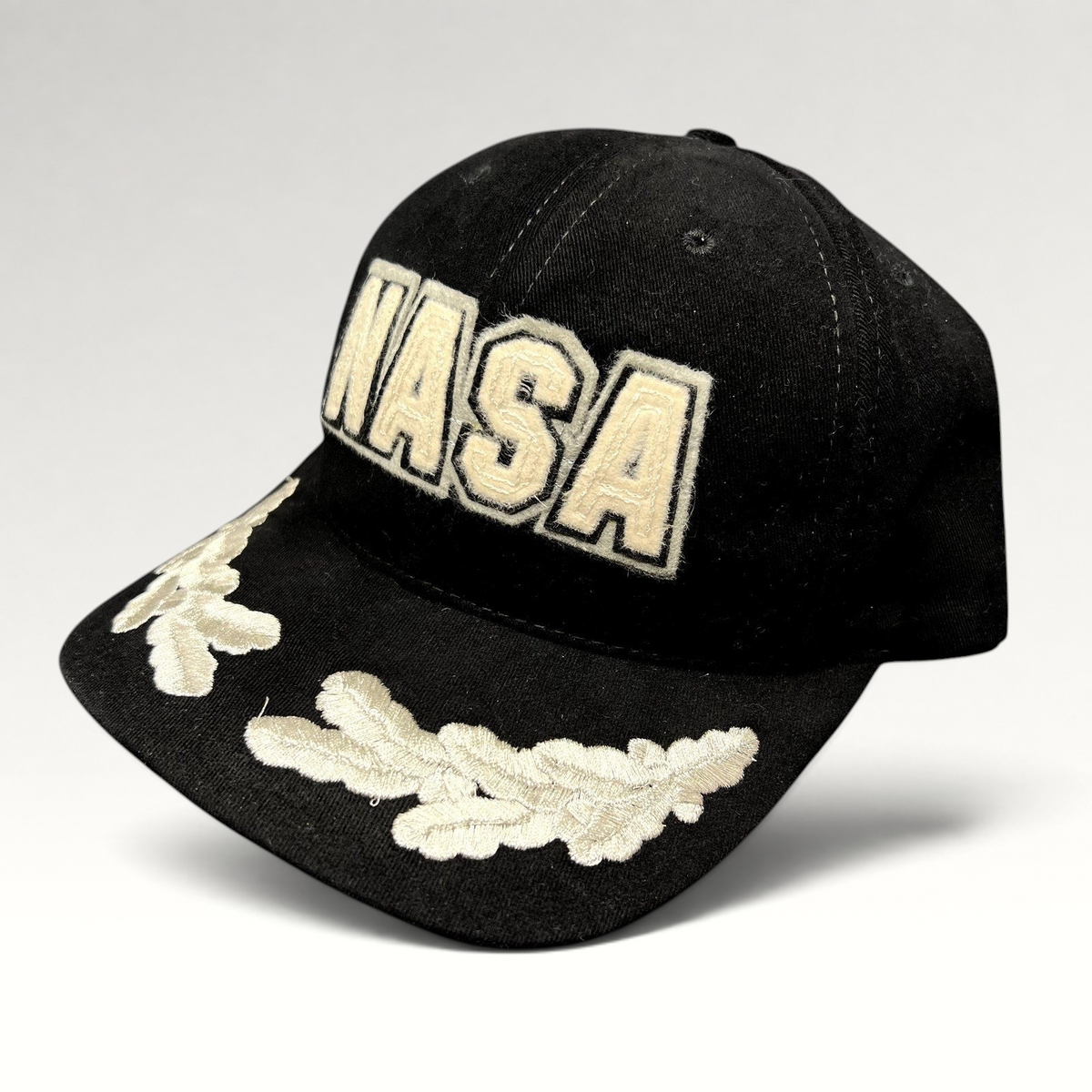 Raree Finds vintage black American Needle NASA strapback hat with cream embroidered logo and leaf brim detailing.