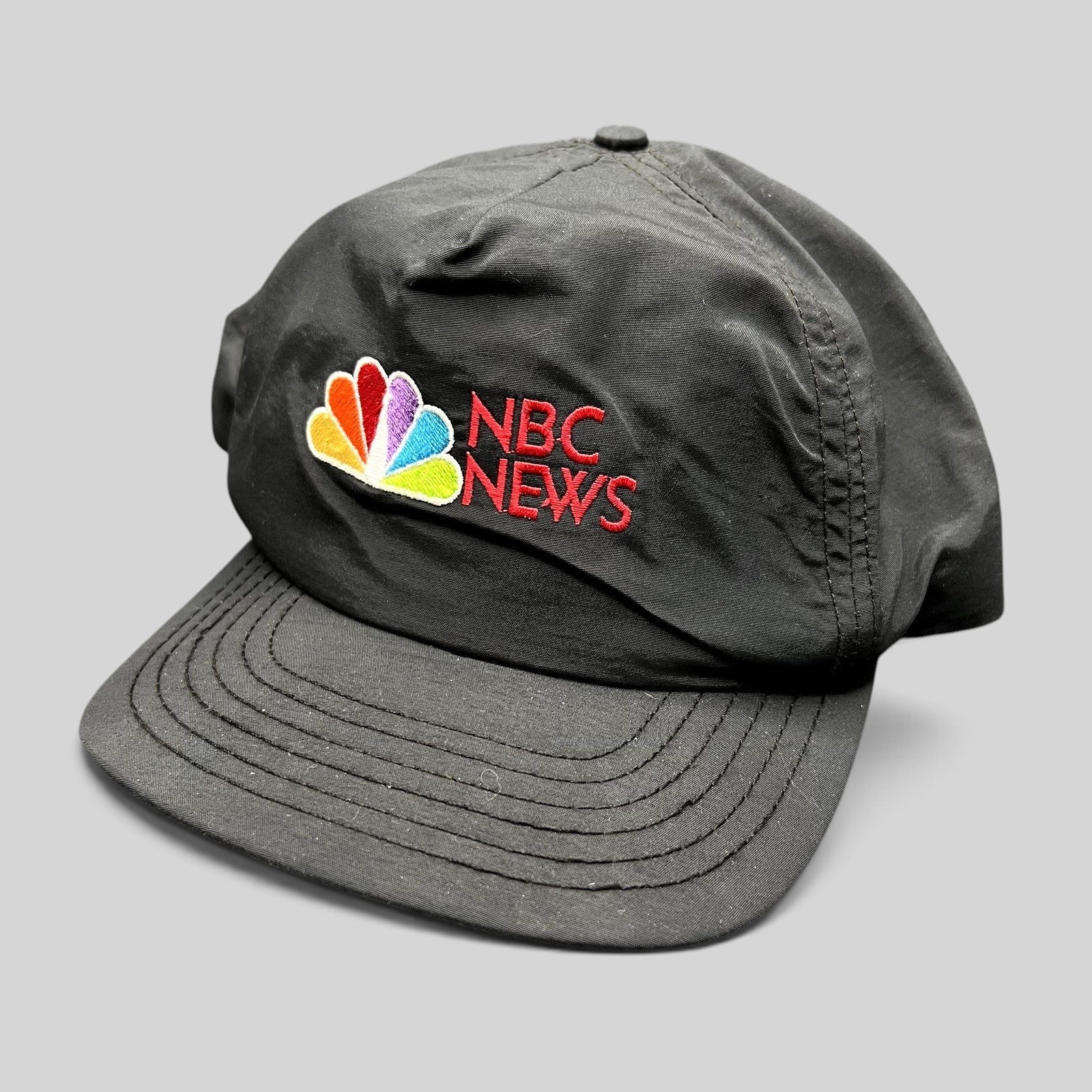 Raree Finds vintage 90s black nylon NBC News snapback hat with embroidered peacock logo and red lettering