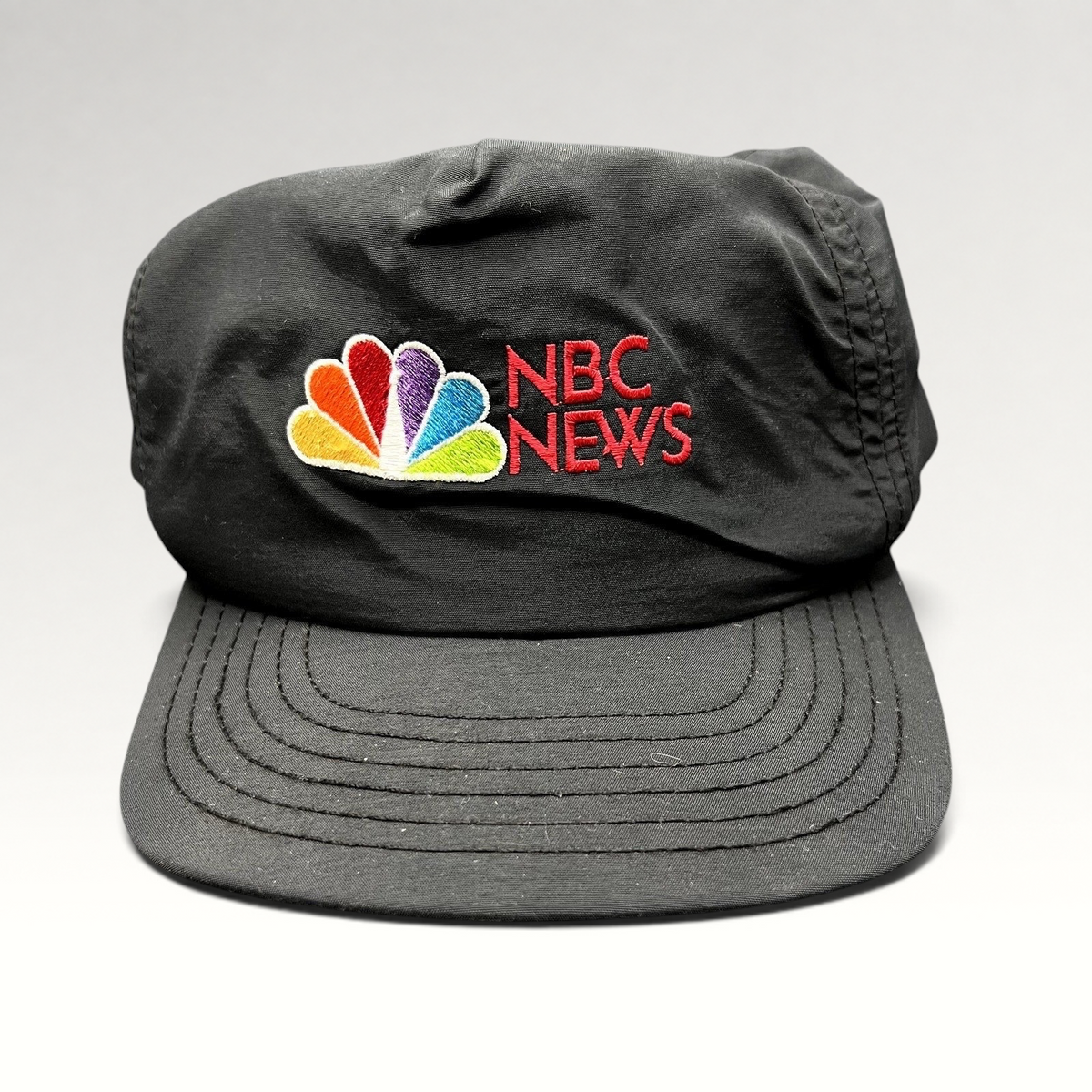 Raree Finds vintage 90s black nylon NBC News snapback hat with embroidered peacock logo and red lettering