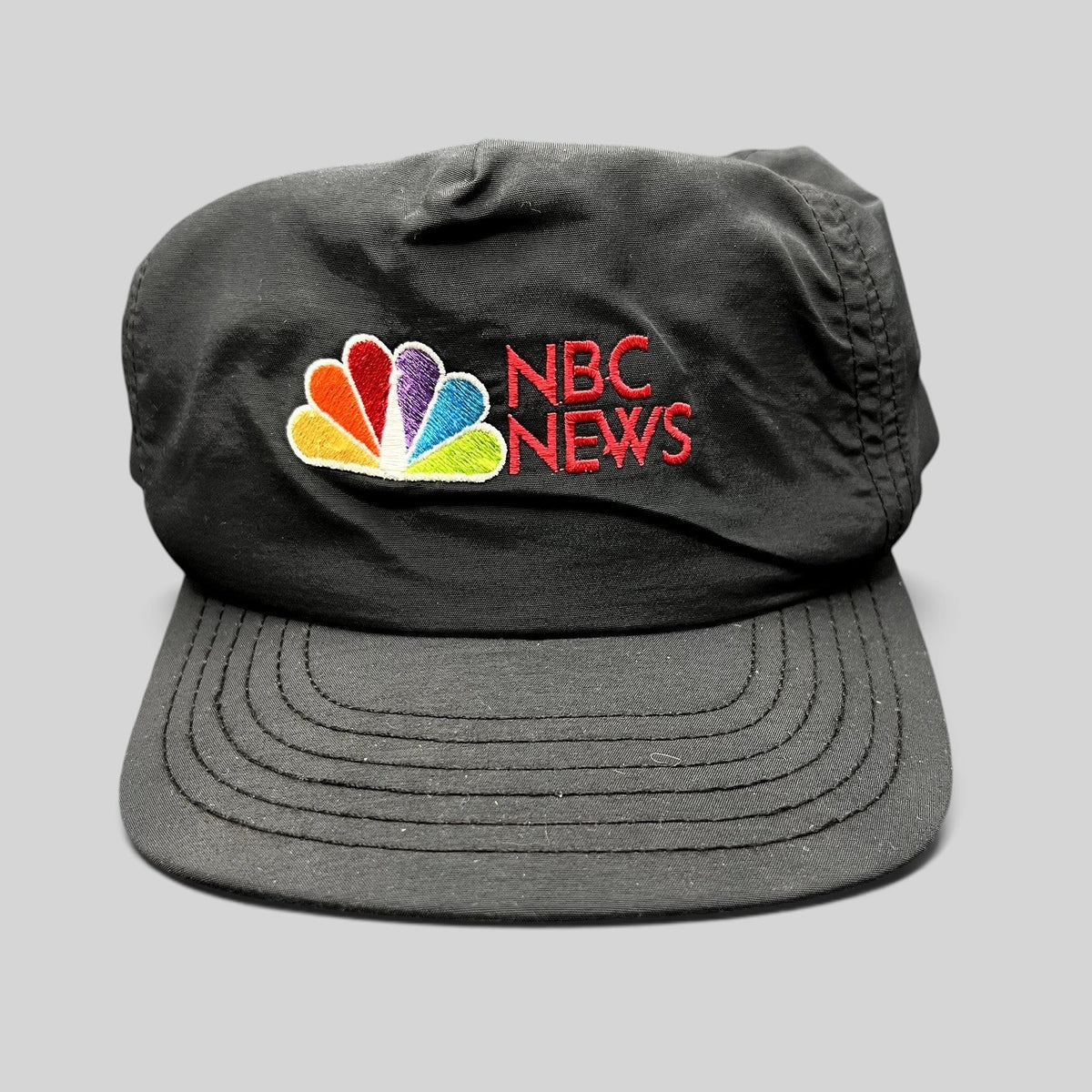 Raree Finds vintage 90s black nylon NBC News snapback hat with embroidered peacock logo and adjustable closure