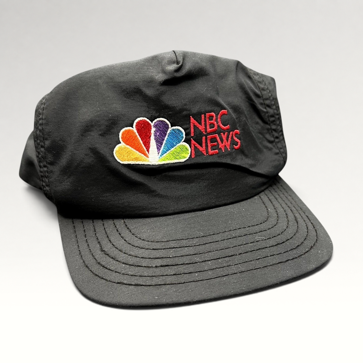 Raree Finds vintage 90s black nylon NBC News snapback hat with embroidered peacock logo and red lettering