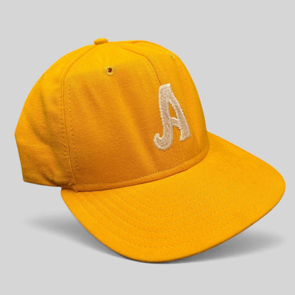Raree Finds vintage New Era Pro Model A snapback hat in gold with embroidered lettering and a green undervisor.
