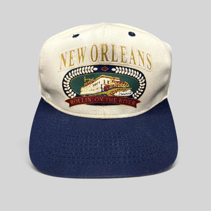 Raree Finds vintage New Orleans snapback hat with cream crown, navy brim, and embroidered riverboat graphic.