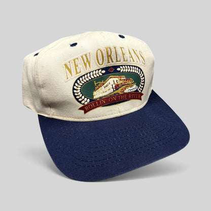 Raree Finds vintage New Orleans snapback hat with embroidered riverboat graphic, cream crown, and navy blue brim.