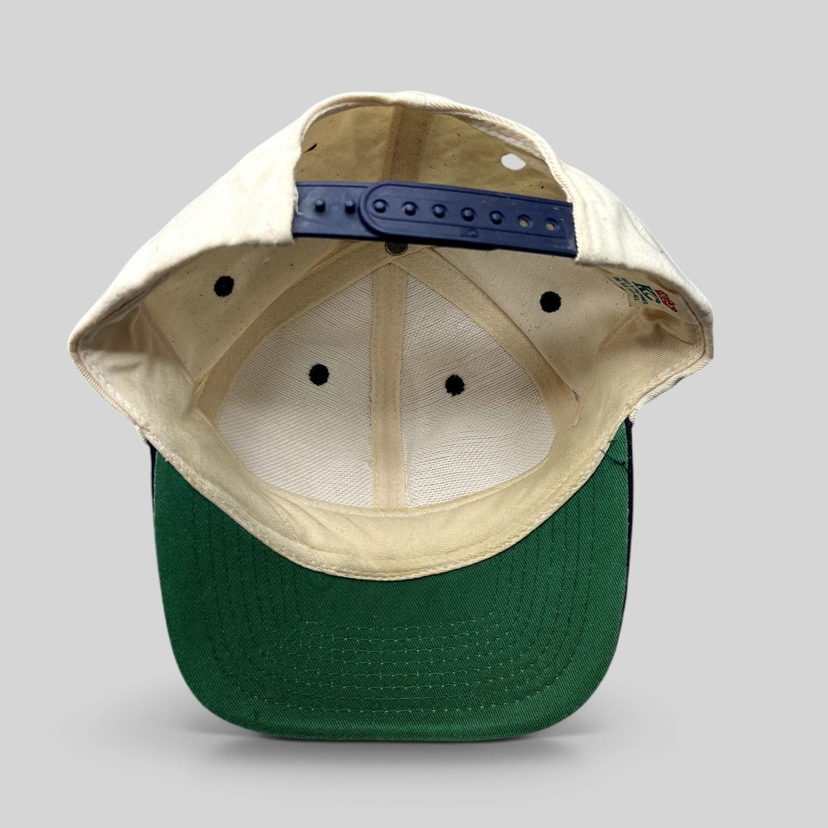 Raree Finds vintage New Orleans snapback hat showing the interior cream crown, navy snap closure, and green undervisor.