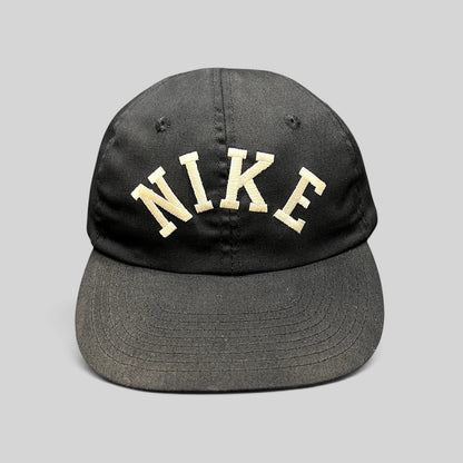 Raree Finds vintage black Nike strapback hat with an oversized arched embroidered logo and green undervisor.