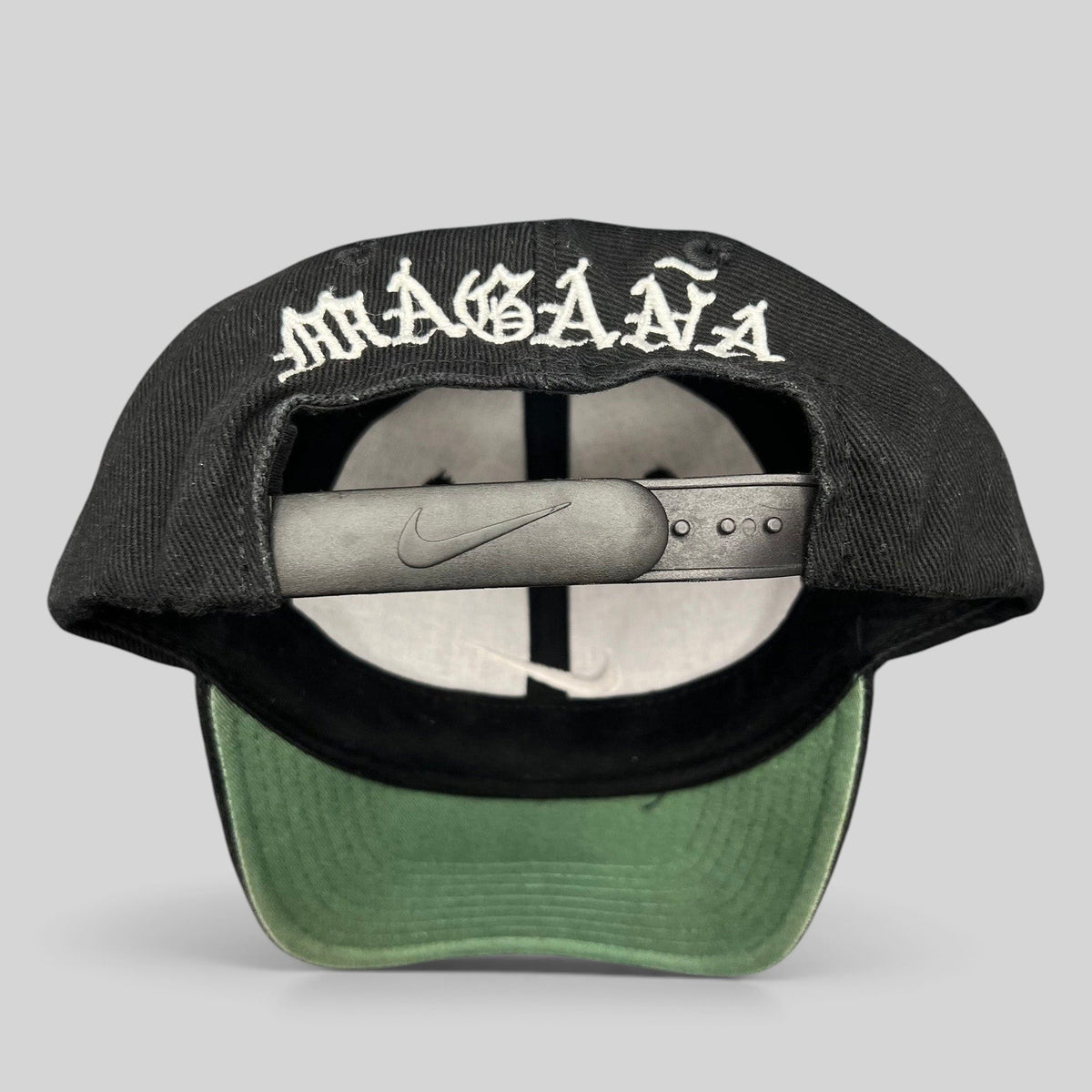 Raree Finds vintage 90s Nike snapback cap in black with Magaña script embroidered on the back and green undervisor.