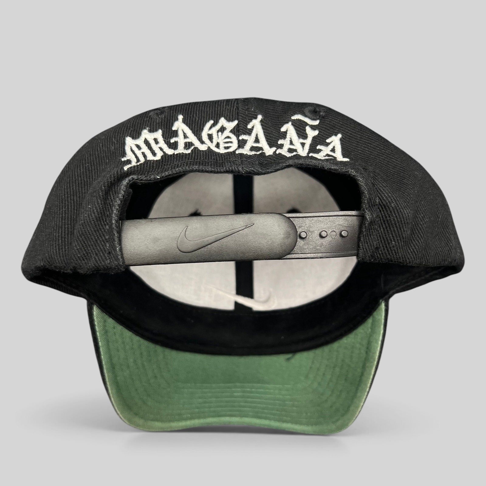 Raree Finds vintage 90s Nike snapback cap in black with Magaña script embroidered on the back and green undervisor.