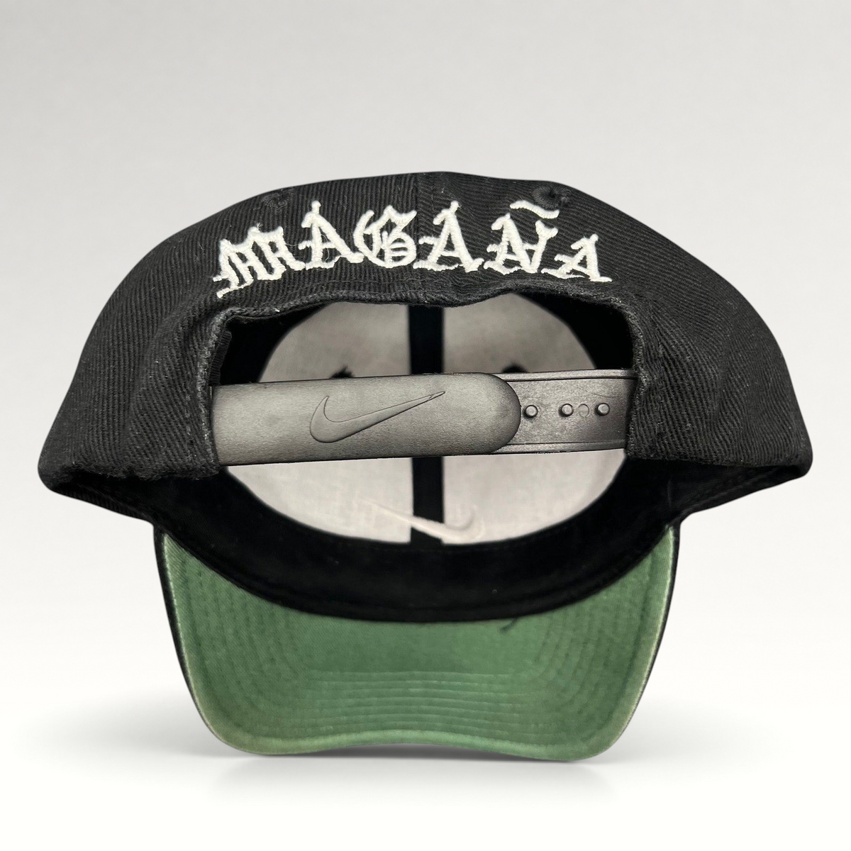 Raree Finds vintage 90s Nike snapback cap in black with Magaña script embroidered on the back and green undervisor.