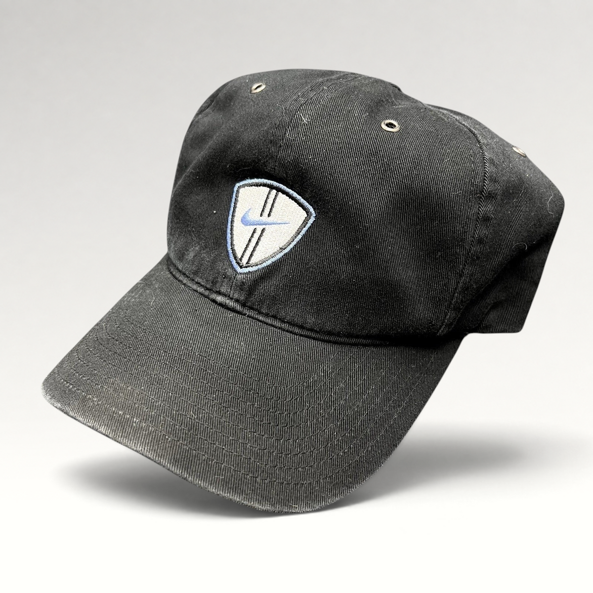 Raree Finds vintage black Nike soccer strapback hat with an embroidered shield crest and blue swoosh logo.
