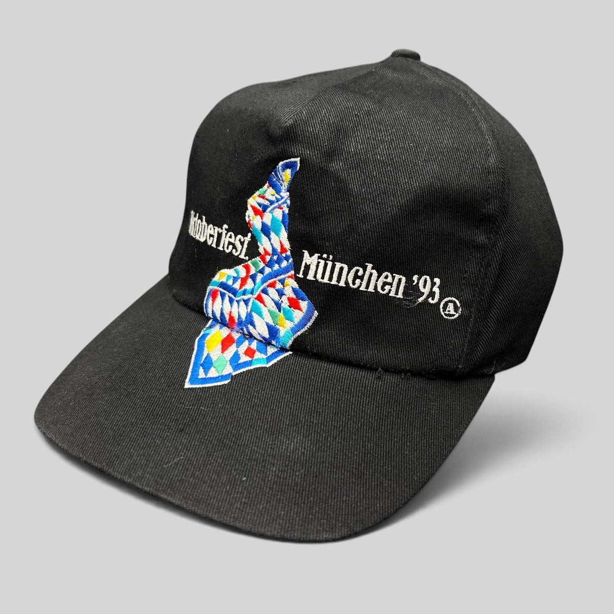 Raree Finds vintage 1993 Oktoberfest Munich black cotton strapback hat with colorful Bavarian geometric embroidery.
