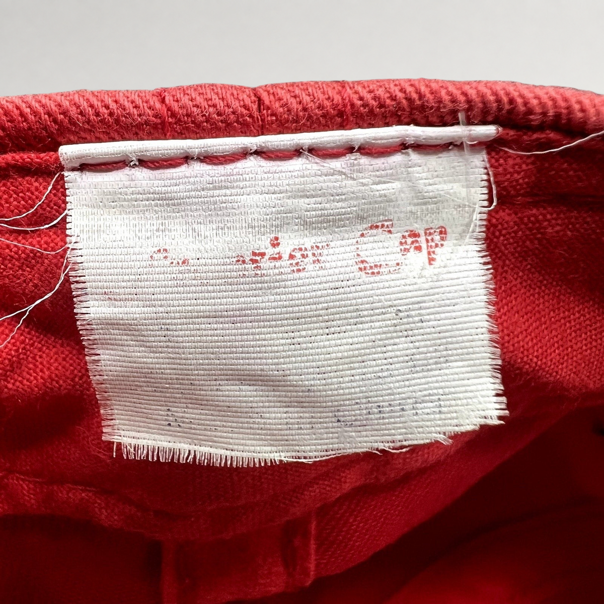 Raree Finds vintage Firestone Racing hat interior white fabric tag with faded red text on a red cotton background