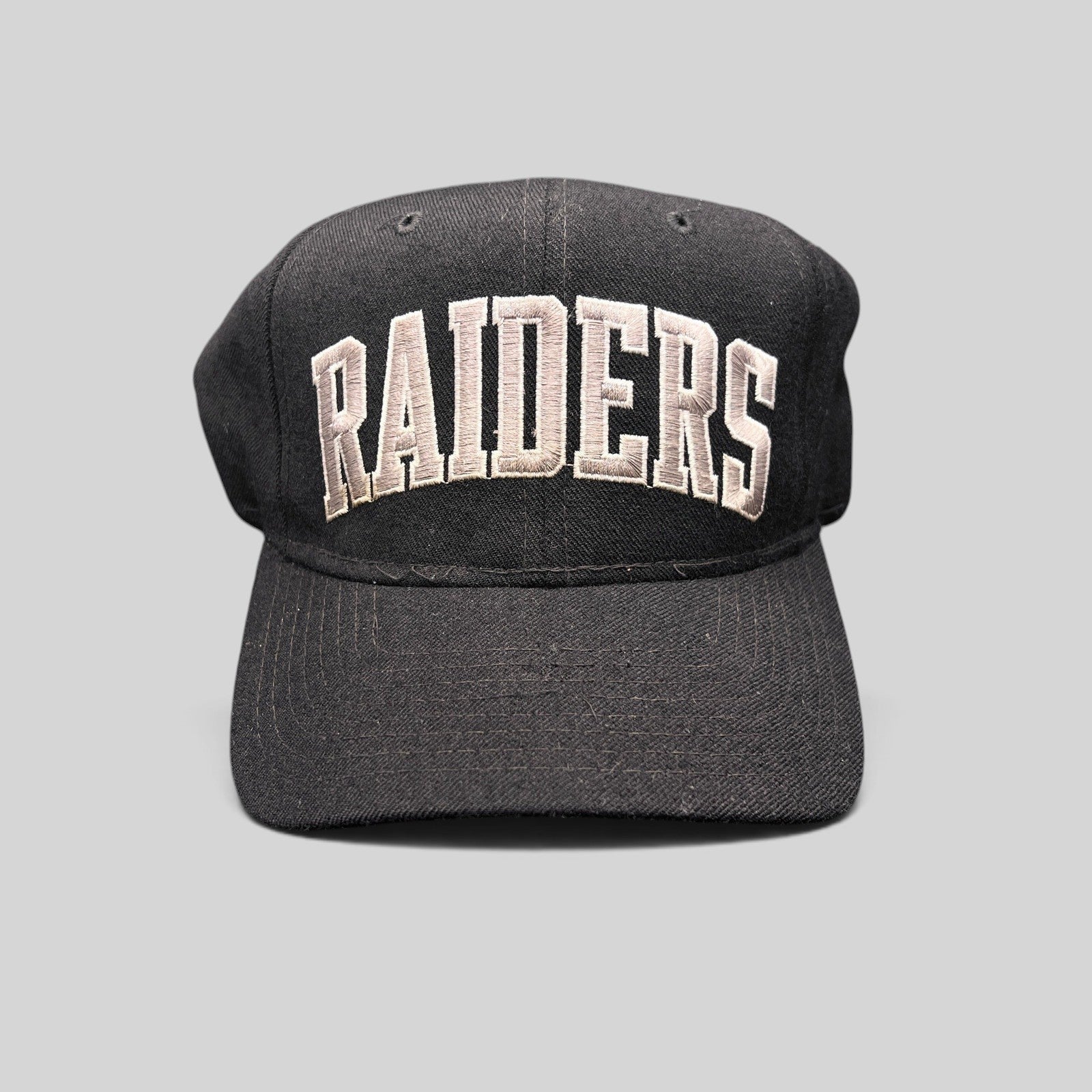 Raree Finds vintage 1990s Starter Los Angeles Raiders wool snapback hat in black with silver arch logo embroidery.
