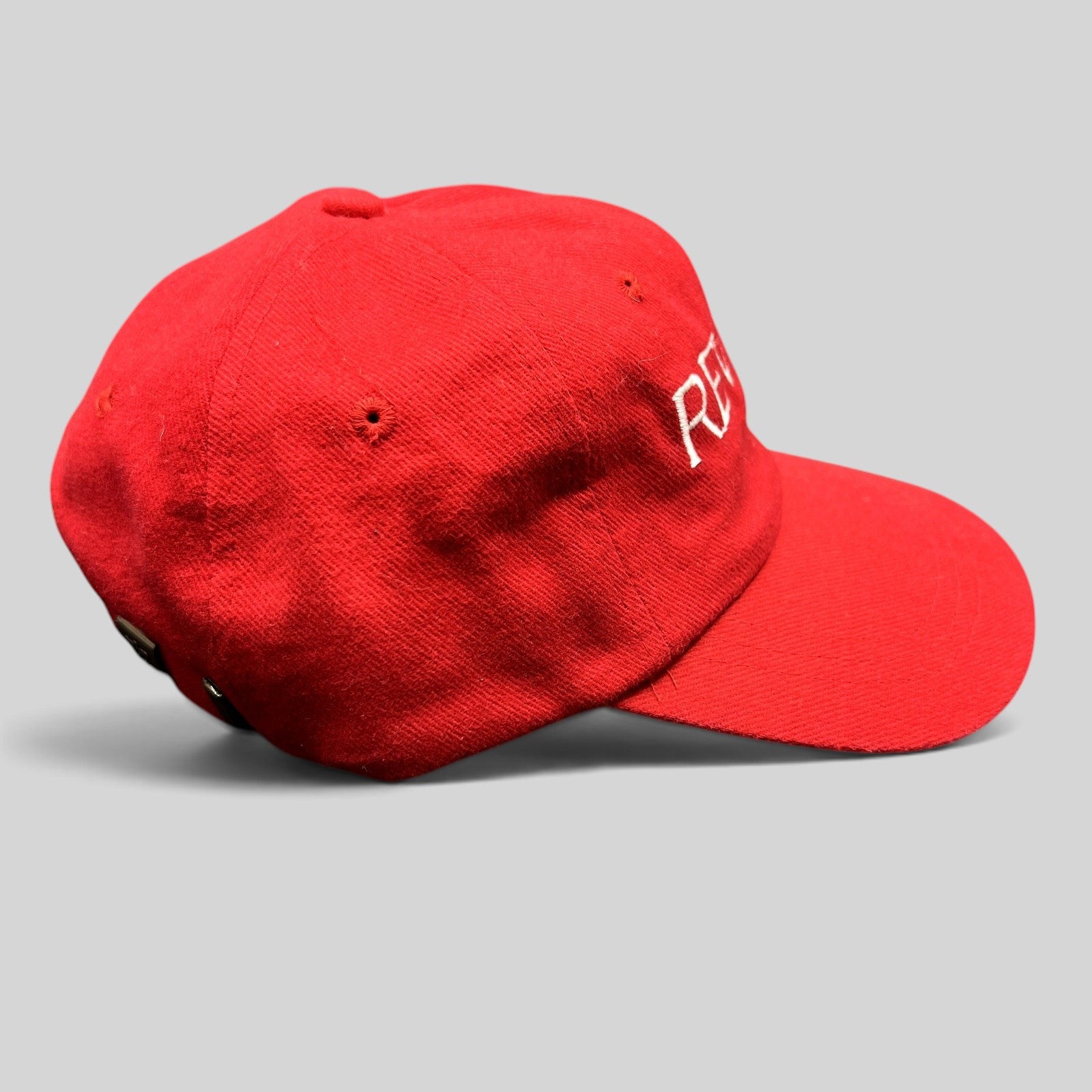 Raree Finds vintage bright red Revlon promotional strapback hat with white embroidered logo, side profile view.