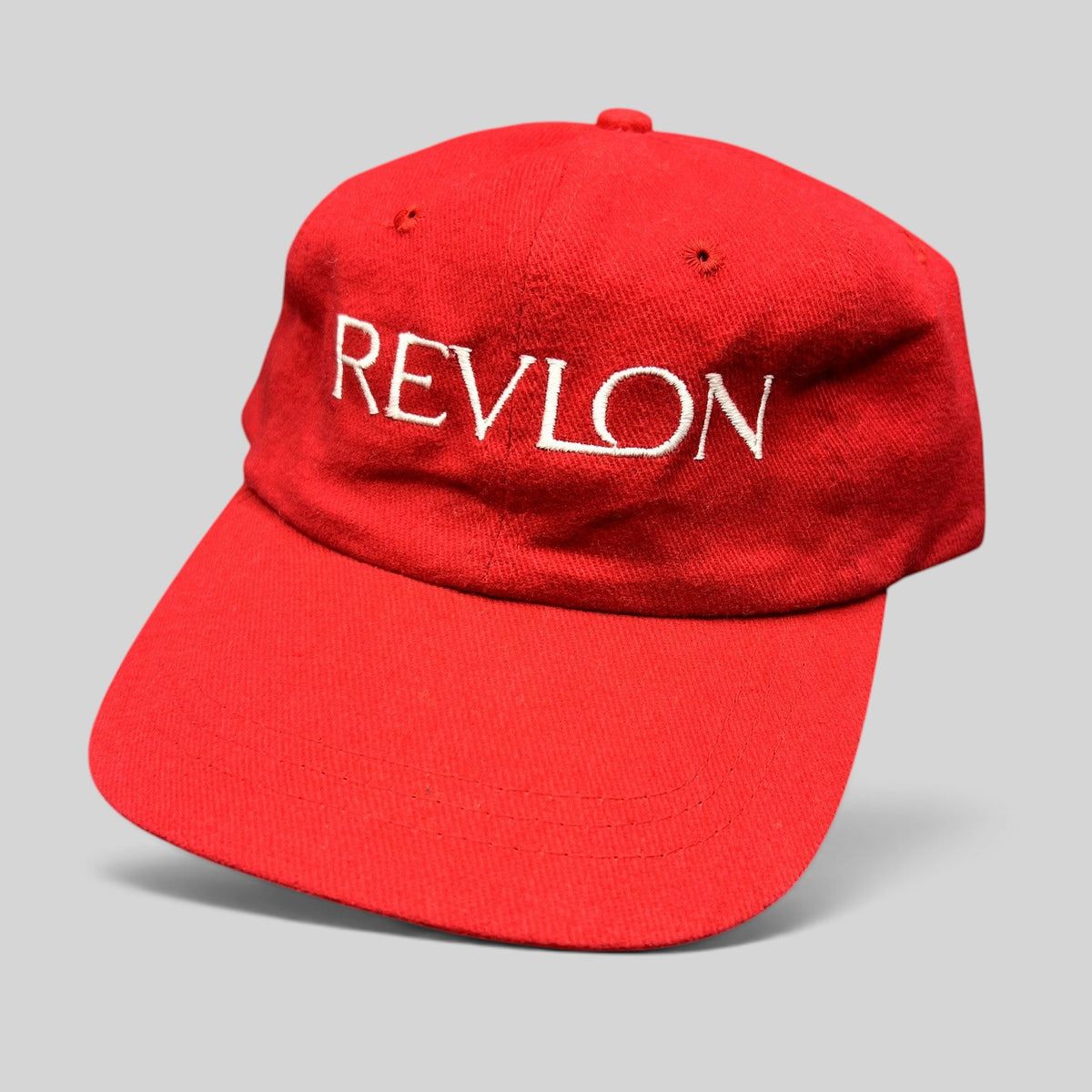 Raree Finds vintage red Revlon promotional strapback hat with white embroidered lettering on the front panel.