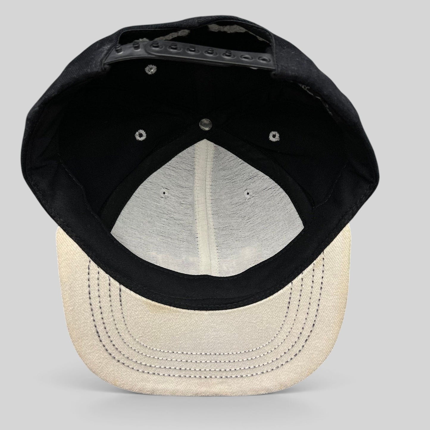 Raree Finds vintage 90s snapback hat interior view showing black crown, light gray brim, and plastic snap closure